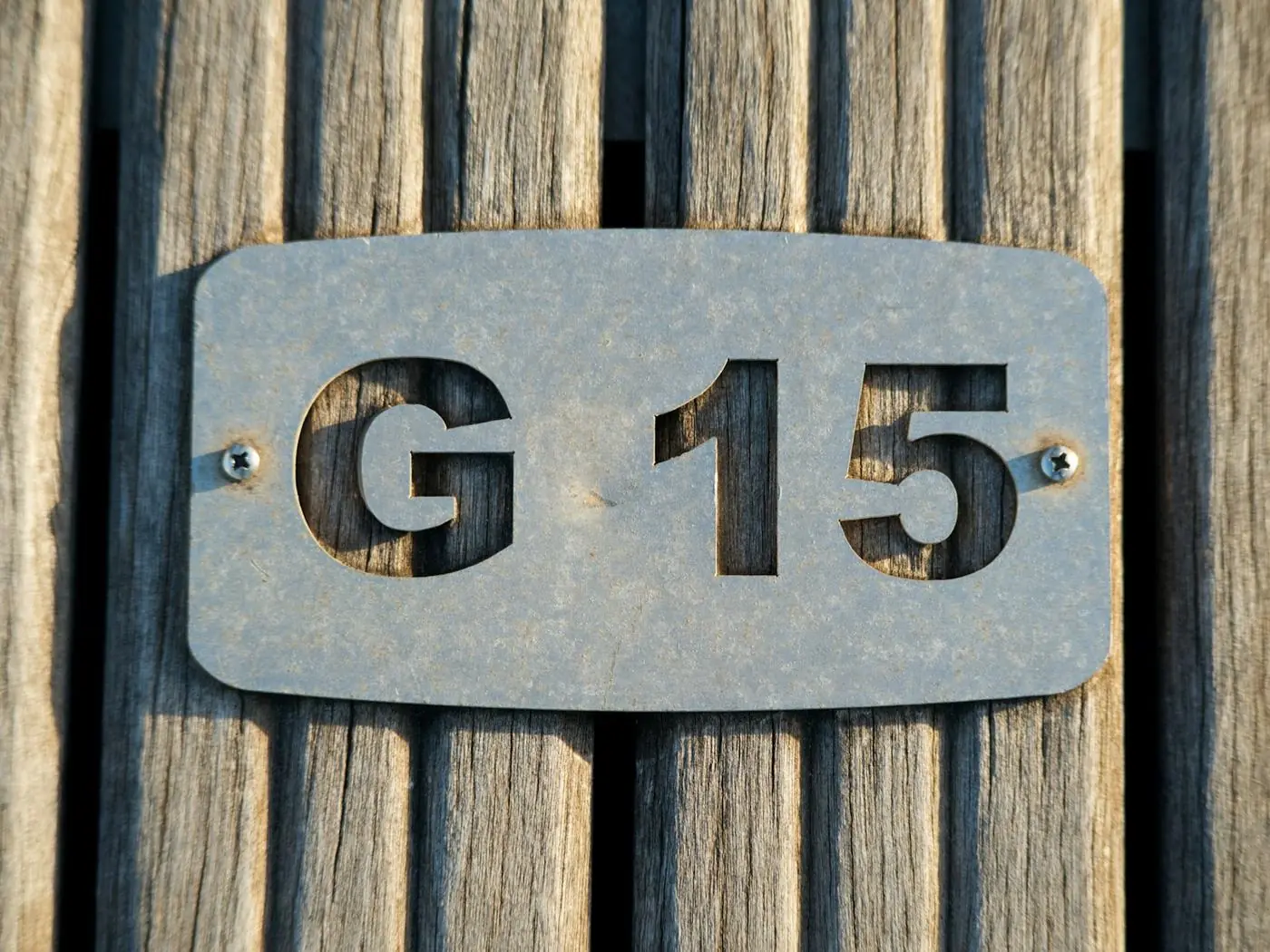 木の板にビスで留めた、G15の文字を切り抜いた金属のプレート