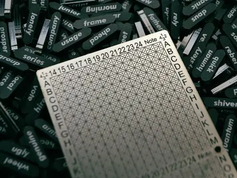 数字とアルファベットの目盛りが入った金属の板と、文字の入った黒いタグ